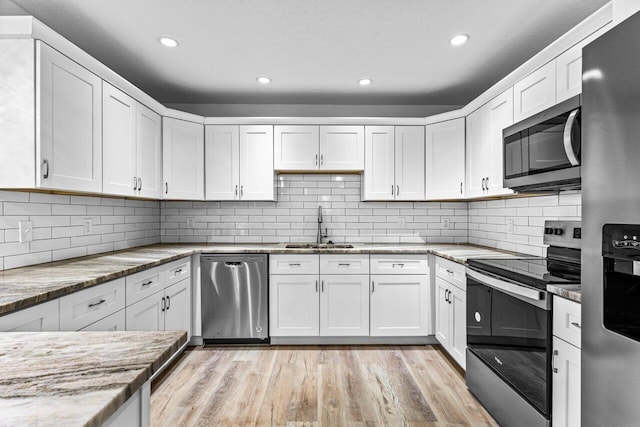 kitchen with white cabinetry, light stone countertops, sink, and appliances with stainless steel finishes