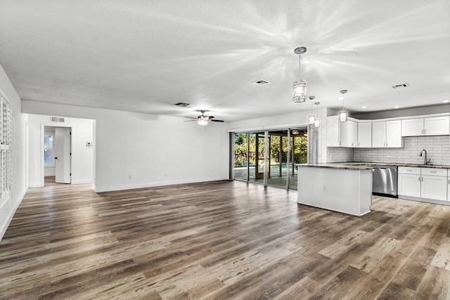 unfurnished living room with a textured ceiling, ceiling fan, sink, and dark wood-type flooring