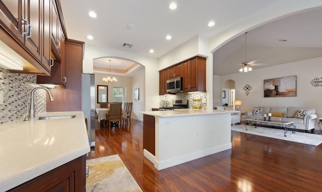 kitchen featuring sink, dark wood-type flooring, stainless steel appliances, kitchen peninsula, and decorative backsplash