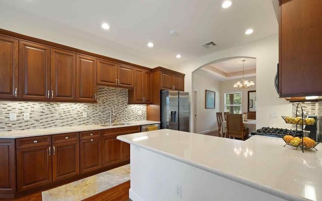 kitchen featuring appliances with stainless steel finishes, backsplash, sink, an inviting chandelier, and dark hardwood / wood-style floors