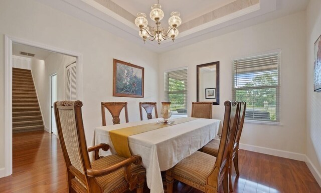 dining room with a chandelier, hardwood / wood-style floors, and a tray ceiling