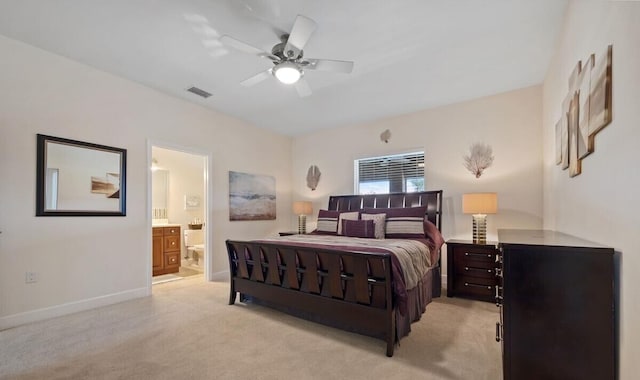 bedroom with ceiling fan, light carpet, and ensuite bath