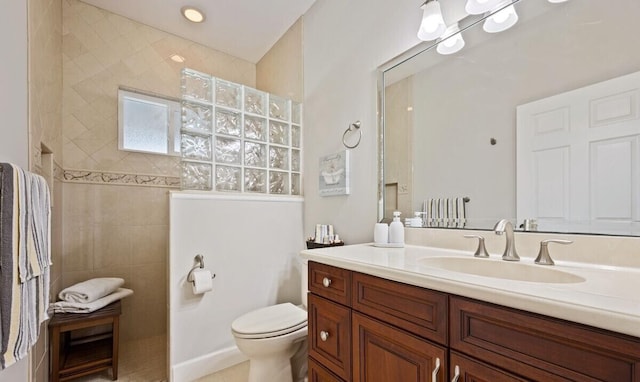 bathroom with tiled shower, vanity, toilet, and tile patterned flooring