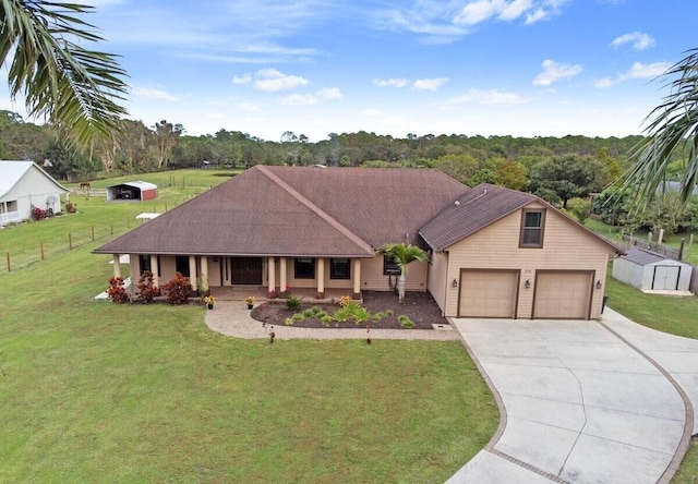 ranch-style house featuring covered porch, an outbuilding, a garage, and a front lawn