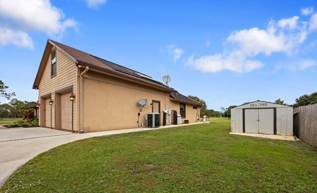 view of home's exterior with central AC unit, a garage, a storage shed, and a lawn