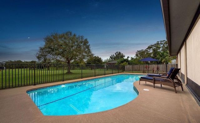 pool at dusk featuring a lawn and a patio