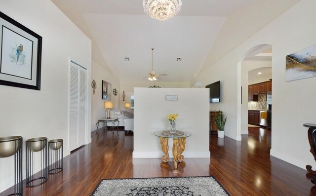 corridor with dark wood-type flooring, lofted ceiling, and a notable chandelier