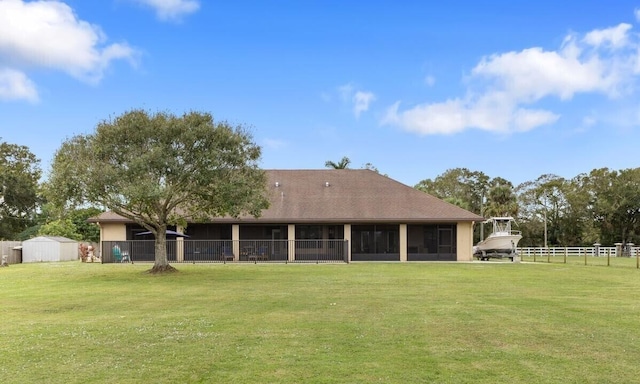 rear view of house with a storage unit and a yard