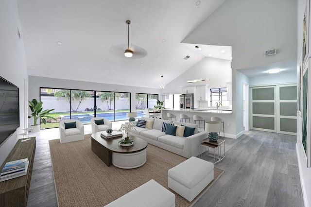 living room featuring light hardwood / wood-style floors, high vaulted ceiling, and sink