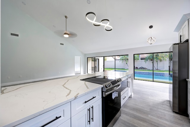 kitchen with vaulted ceiling, light stone countertops, decorative light fixtures, white cabinetry, and stainless steel appliances