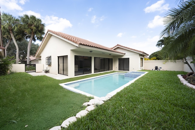 rear view of house with a yard and a fenced in pool