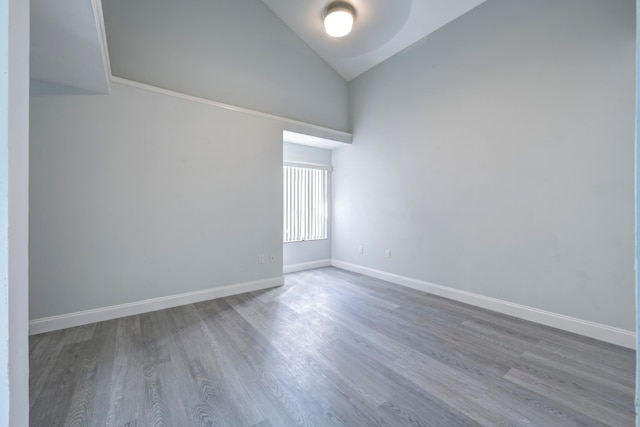 spare room featuring wood-type flooring and vaulted ceiling