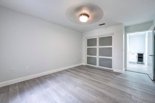 unfurnished room featuring light hardwood / wood-style floors and wine cooler