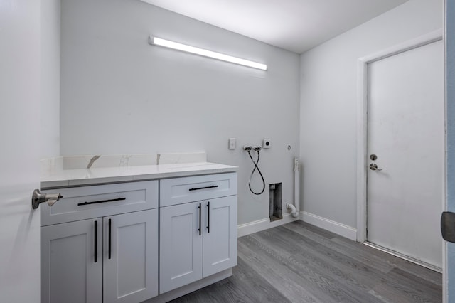 clothes washing area featuring hookup for an electric dryer, hardwood / wood-style flooring, and cabinets