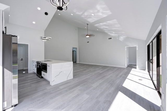 kitchen with light stone counters, white cabinetry, hanging light fixtures, and stainless steel refrigerator