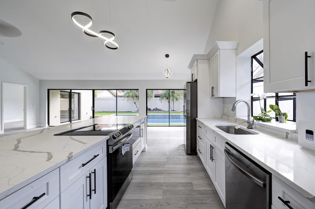 kitchen with light stone counters, stainless steel appliances, sink, pendant lighting, and white cabinets