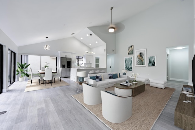 living room with light hardwood / wood-style floors, high vaulted ceiling, and ceiling fan