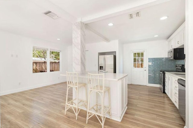 6312 Garden Ave, West Palm Beach, FL 33405 - kitchen featuring appliances with stainless steel finishes, plenty of natural light, light wood-type flooring, a breakfast bar, and beam ceiling