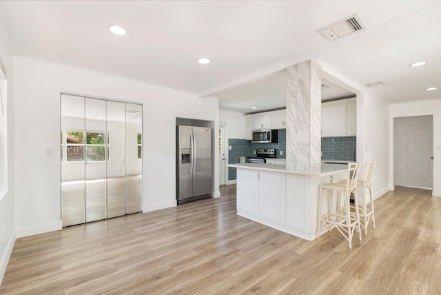 6312 Garden Ave, West Palm Beach, FL 33405 - kitchen featuring appliances with stainless steel finishes, light countertops, tasteful backsplash, light wood-style floors, and baseboards