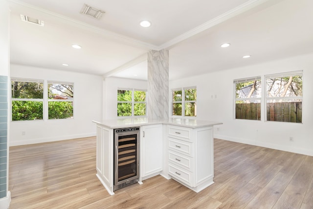 kitchen featuring kitchen peninsula, white cabinets, beverage cooler, and light hardwood / wood-style floors