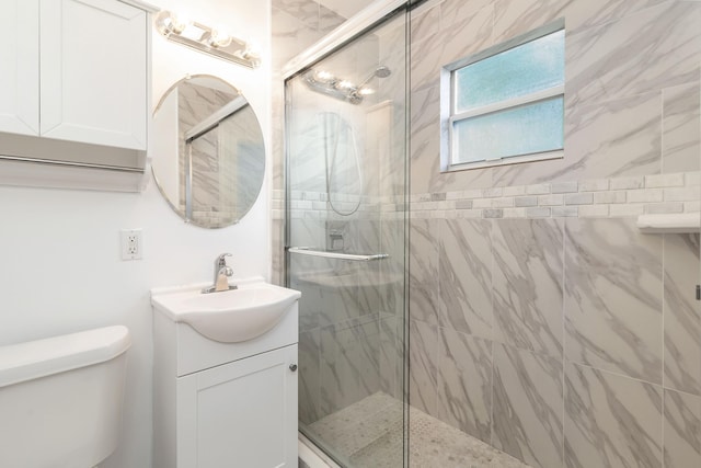 bathroom with vanity, toilet, and a shower with door