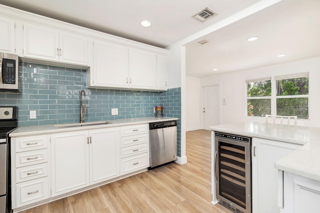 6312 Garden Ave, West Palm Beach, FL 33405 - kitchen featuring wine cooler, appliances with stainless steel finishes, a sink, light countertops, and light wood-style floors