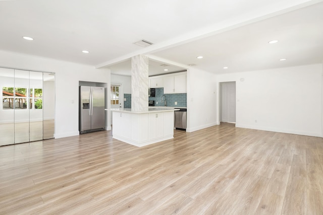 kitchen featuring backsplash, sink, appliances with stainless steel finishes, a kitchen island, and white cabinetry