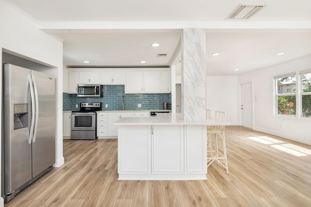 6312 Garden Ave, West Palm Beach, FL 33405 - kitchen featuring stainless steel appliances, light countertops, backsplash, white cabinetry, and light wood-style floors