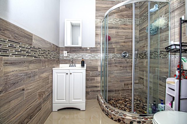 bathroom with vanity, a shower with door, and tile walls