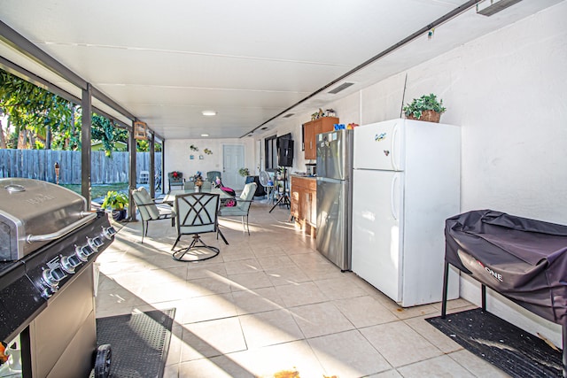 interior space with stainless steel fridge, light tile patterned floors, and white refrigerator