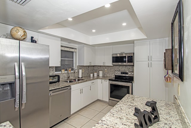 kitchen with sink, decorative backsplash, light stone countertops, appliances with stainless steel finishes, and white cabinetry