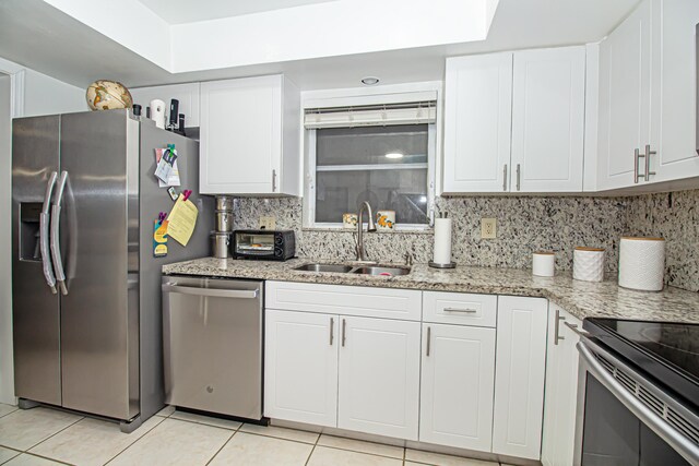 kitchen with white cabinetry, sink, light stone counters, and appliances with stainless steel finishes