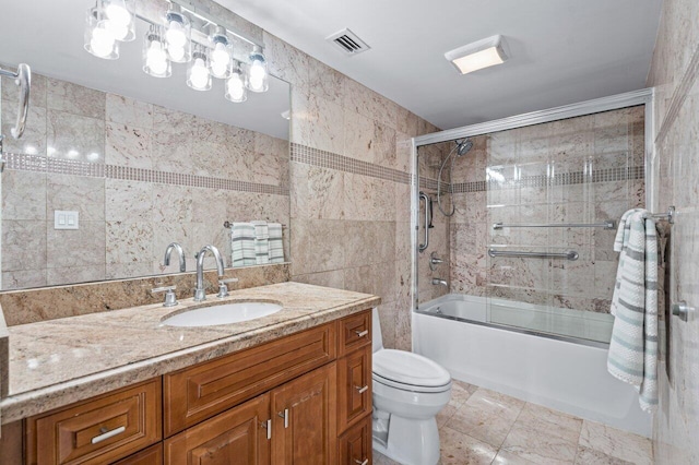 full bathroom with shower / bath combination with glass door, vanity, tile walls, and toilet