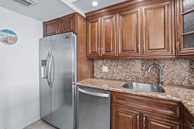 kitchen with backsplash, light stone counters, sink, and stainless steel appliances