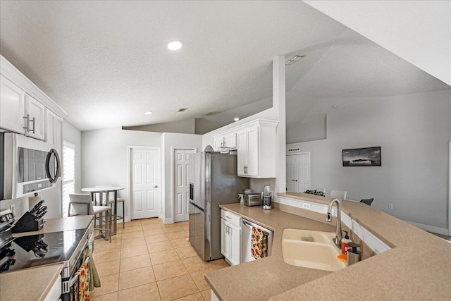 kitchen with white cabinetry, sink, appliances with stainless steel finishes, and vaulted ceiling