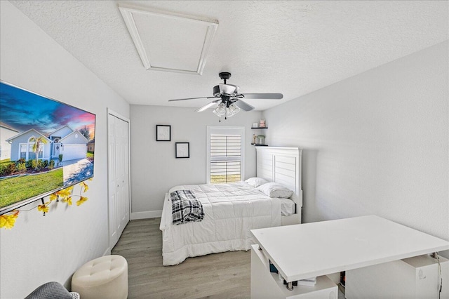 bedroom featuring ceiling fan, a closet, a textured ceiling, and light hardwood / wood-style flooring