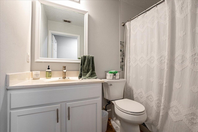 bathroom with a textured ceiling, vanity, and toilet