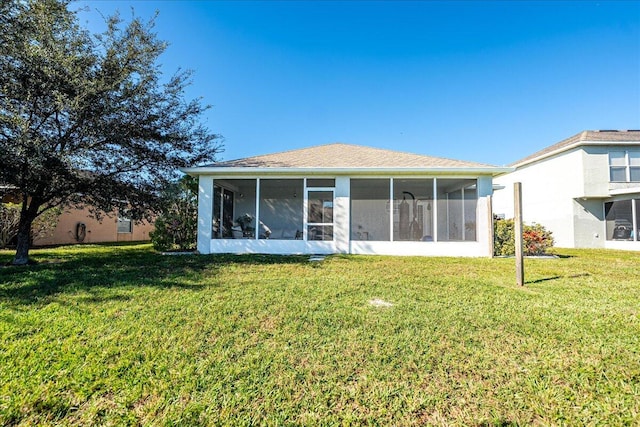 back of property with a yard and a sunroom