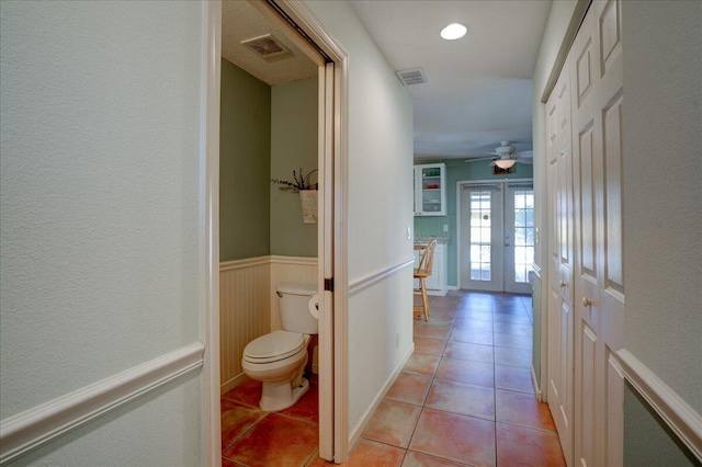 interior space with tile patterned flooring, ceiling fan, toilet, and french doors