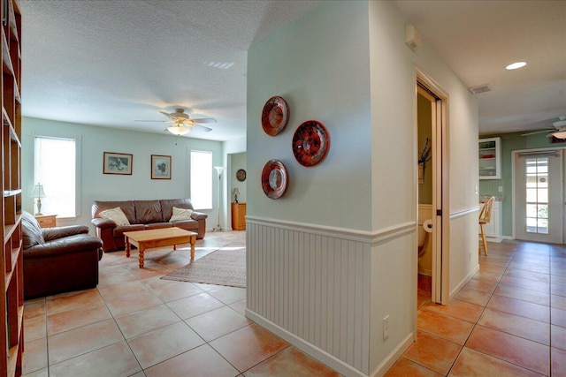 tiled living room with a textured ceiling and ceiling fan