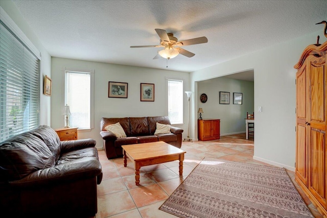 living room featuring ceiling fan, light tile patterned flooring, and a textured ceiling