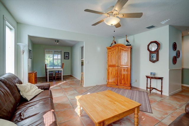 living room with ceiling fan, light tile patterned flooring, and a textured ceiling