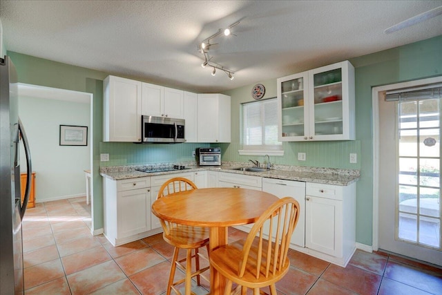 kitchen featuring sink, stainless steel appliances, light stone counters, a textured ceiling, and white cabinets