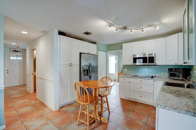 kitchen with backsplash, stainless steel appliances, white cabinetry, and sink