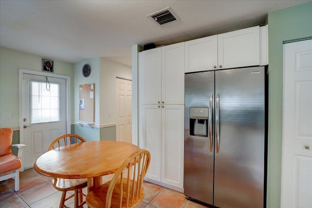 kitchen with white cabinetry, stainless steel fridge with ice dispenser, a textured ceiling, and light tile patterned floors