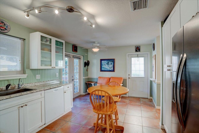 kitchen with white cabinets, white dishwasher, sink, light stone counters, and stainless steel fridge with ice dispenser