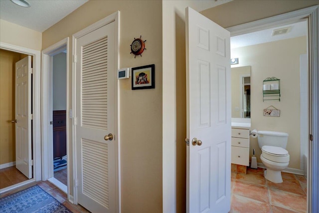 bathroom with tile patterned flooring, vanity, toilet, and a textured ceiling