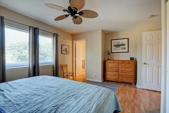 bedroom with ceiling fan, light hardwood / wood-style floors, a textured ceiling, and ensuite bath