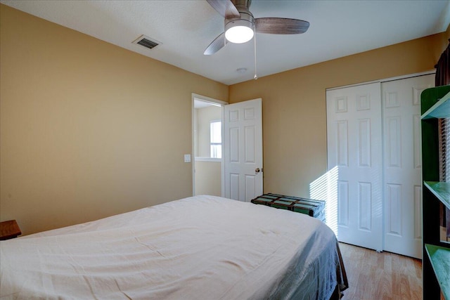 bedroom with a closet, light hardwood / wood-style flooring, and ceiling fan