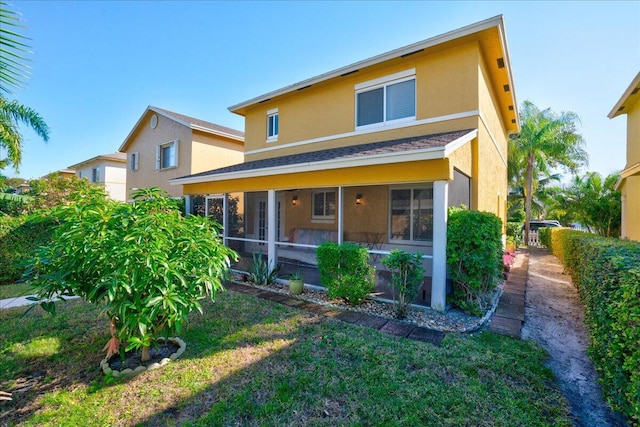 rear view of property with a sunroom and a yard